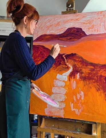 Helen Morgan painting a warm-toned fell landscape with a stone path