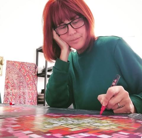 Close-up of Helen Morgan drawing a geometric pattern in red and pink ink